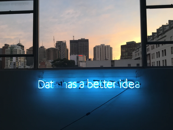 View from a window across the city. In the foreground a neon light says 'Data has a better idea'.
