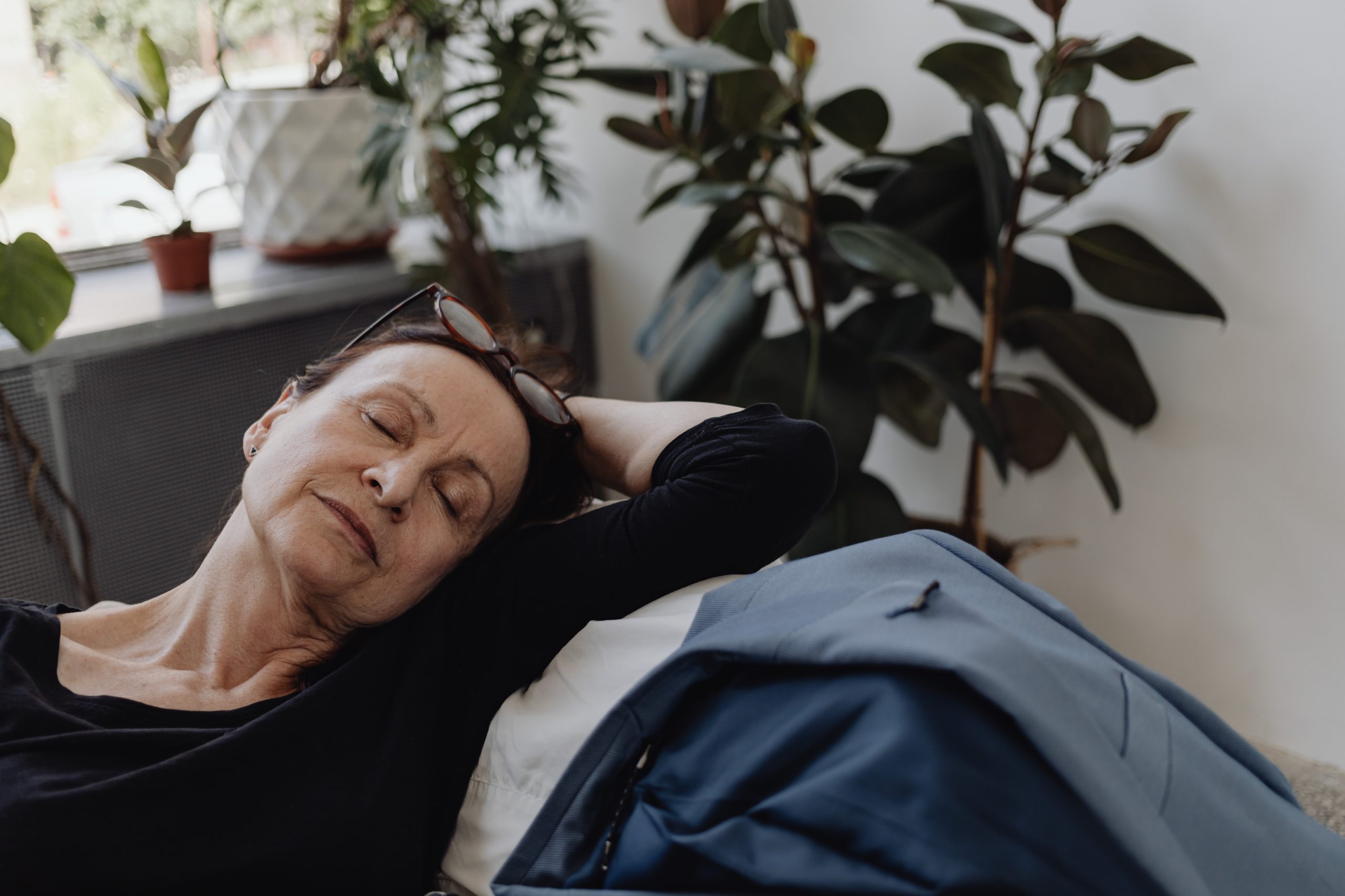 A woman resting on a sofa with her eyes closed