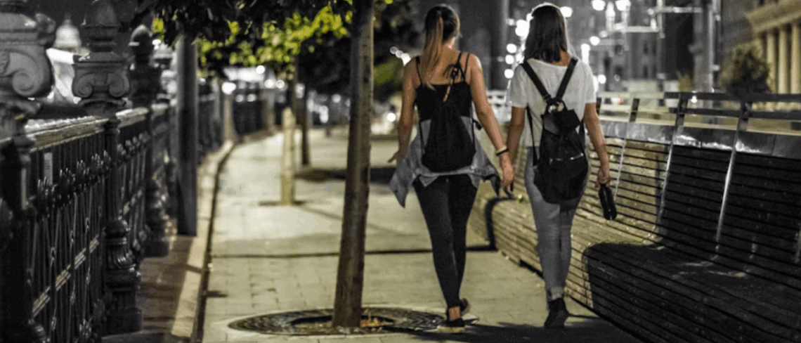 Two people walking down an urban street at night