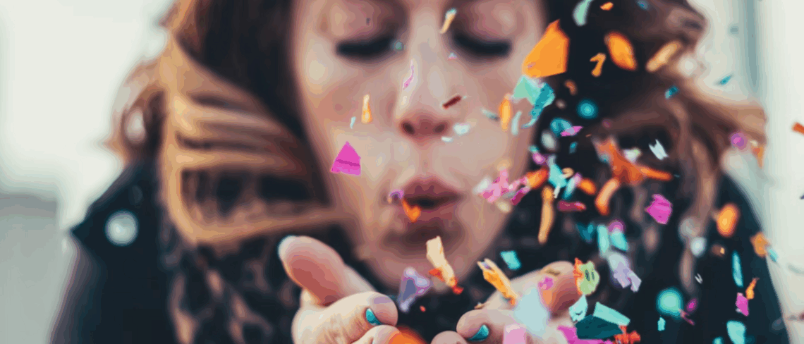 Person blowing confetti from cupped hands