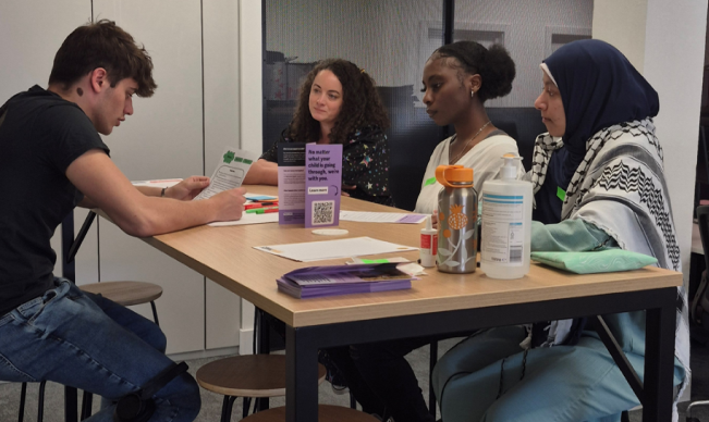 A picture of four young people sat around a desk, taken as part of this project's participatory workshops