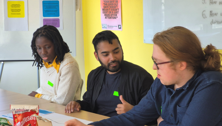 A picture of three young people discussing around a table, the picture was taken as part of the participatory workshops of this project
