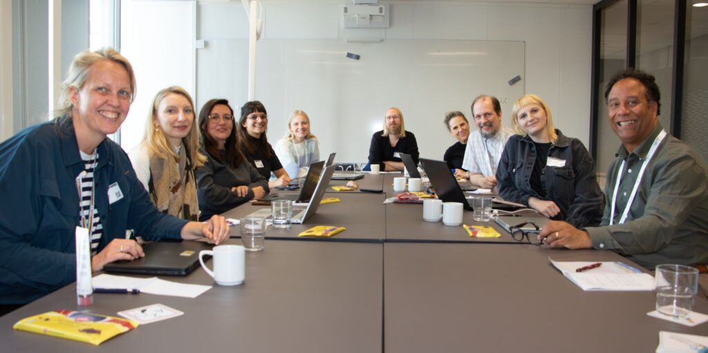 A photograph at the CESSDA conference with the CESSDA comms team sat around a table on their laptops
